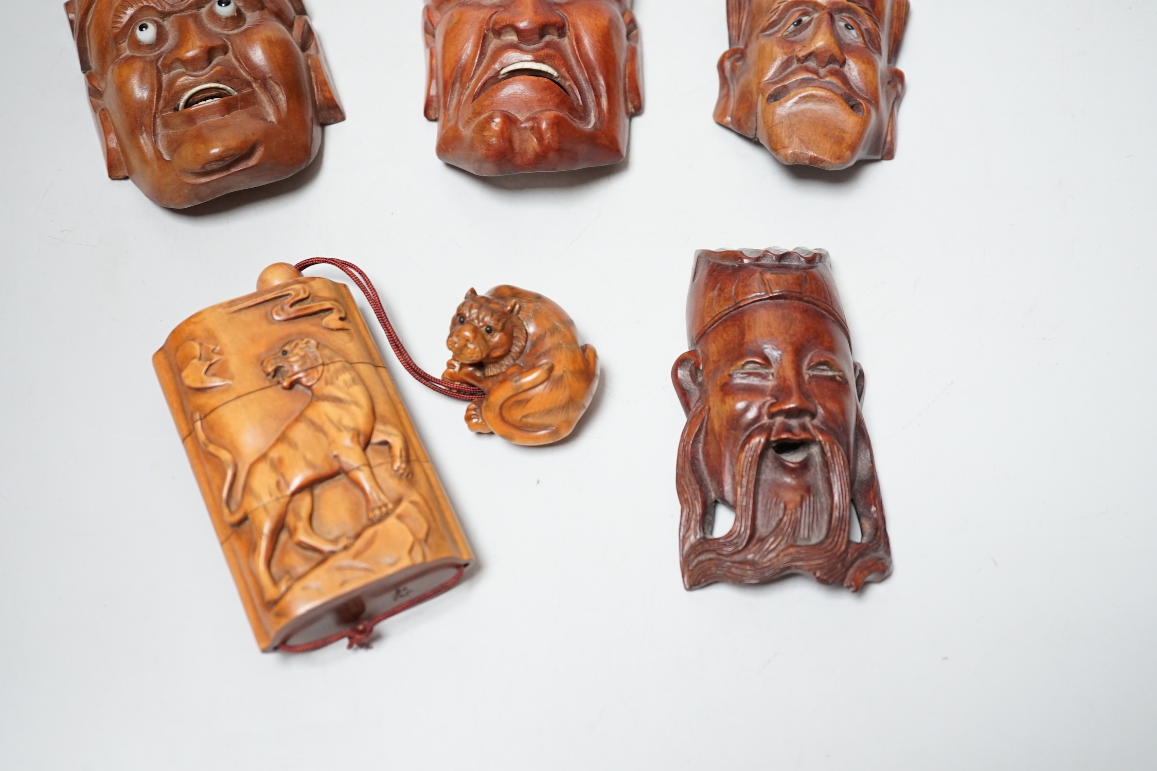 A group of hardwood models of noh masks and a similar inro, 9cm and netsuke